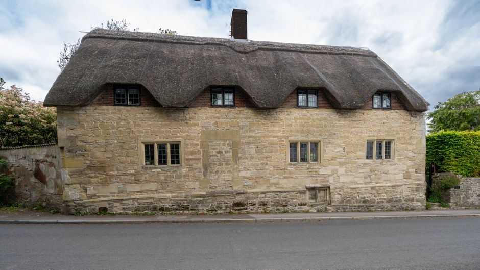View of a traditional thatched-roof cottage in Codford, England, showcasing classic architecture.