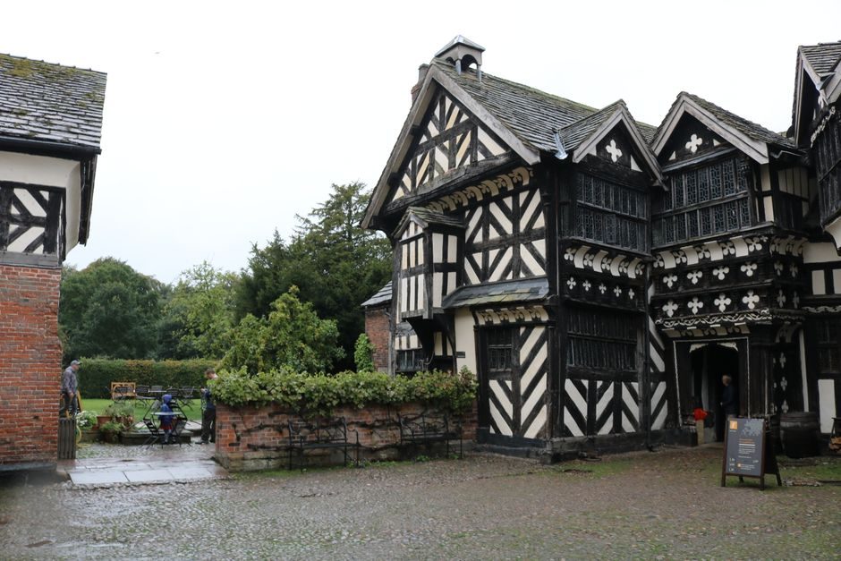 Charming black-and-white Tudor house set in a lush English garden with cobblestone pathway.