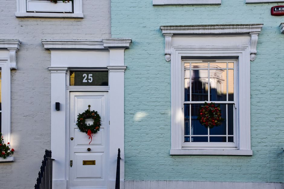 Festive entrance with holiday wreaths on a pastel-colored facade in London, UK.