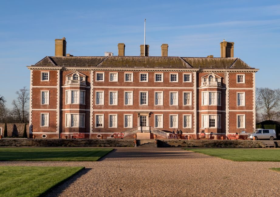 Elegant red brick mansion in England under clear sky, showcasing classic architecture.
