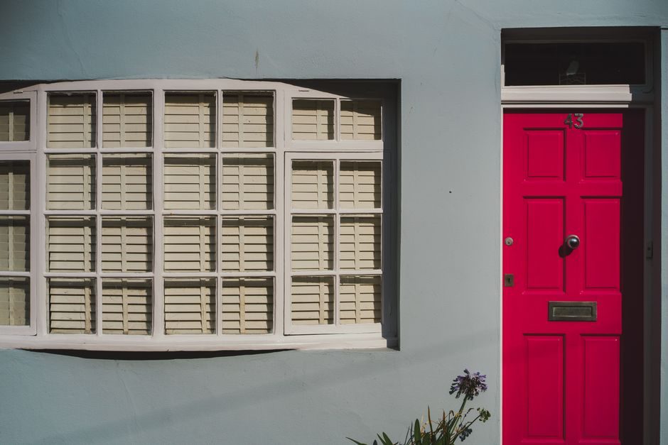 Vibrant red door with house number 43 beside a white window in Brighton, UK.
