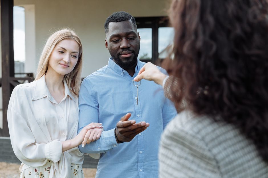Parents handing house keys to their adult child at a new home