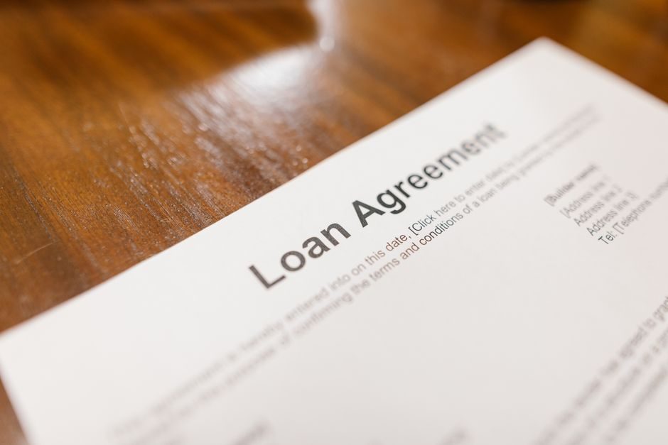 Mortgage application documents spread on a desk with a financial adviser