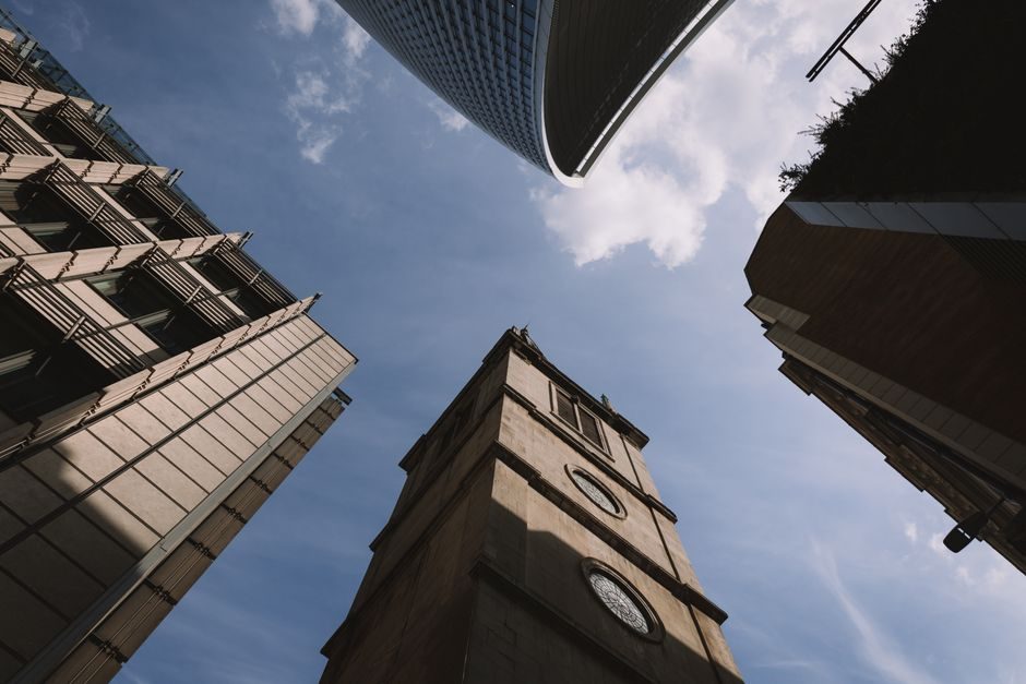 Upward view of diverse architectural styles in London featuring modern skyscrapers and historical buildings.