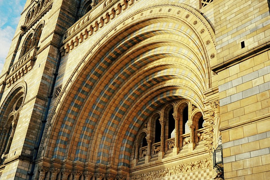 Detailed view of the Natural History Museum's iconic arched stone facade in London, highlighting intricate architectural designs.