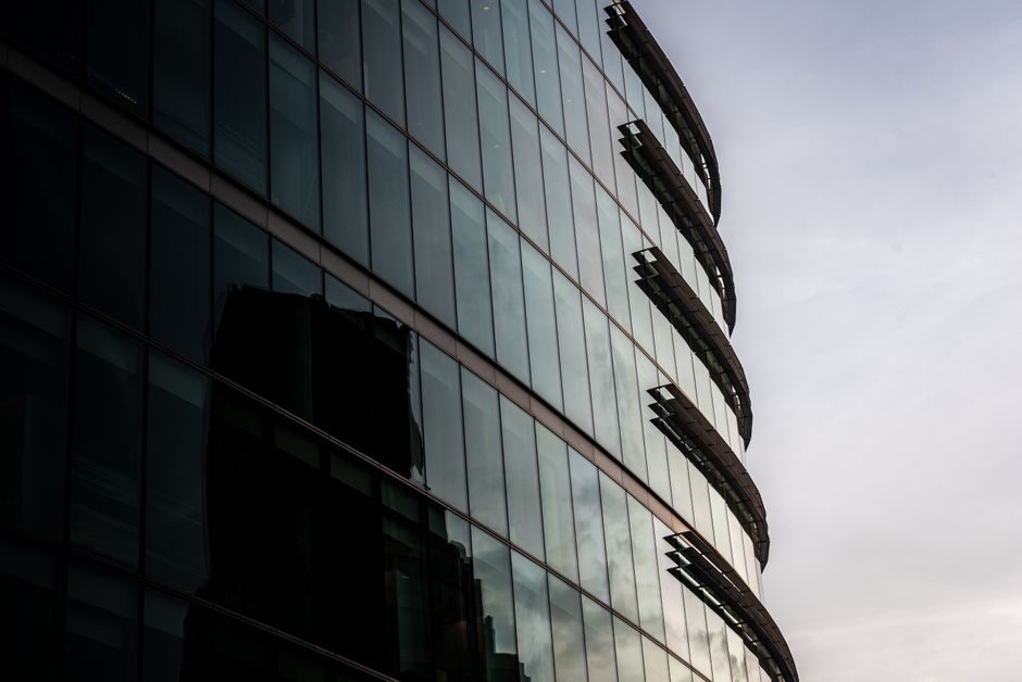 Contemporary glass office building reflecting cityscape in London, UK.