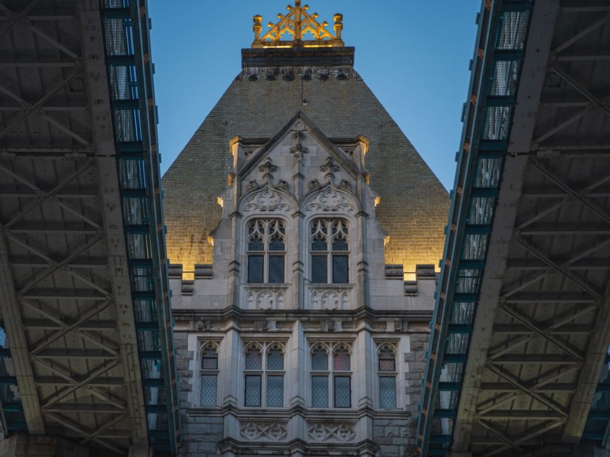 Detailed view of Gothic Revival architectural elements under London's Tower Bridge at dusk.