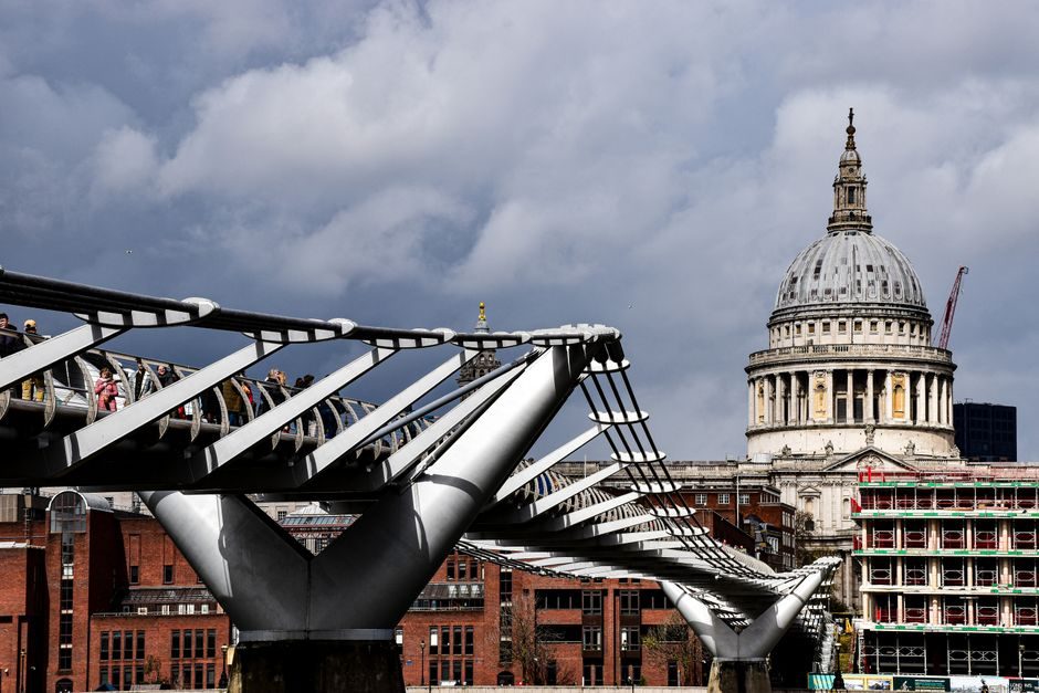 Iconic Millennium Bridge leading to St. Paul's Cathedral under a dramatic sky in London.