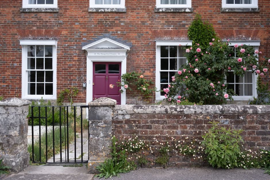 Front view of traditional English brick house with colorful rose garden in Salisbury, England.