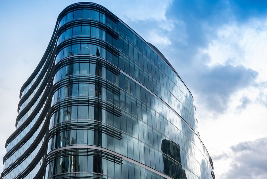 A stunning modern glass building in London, showcasing contemporary architecture against a cloudy sky.