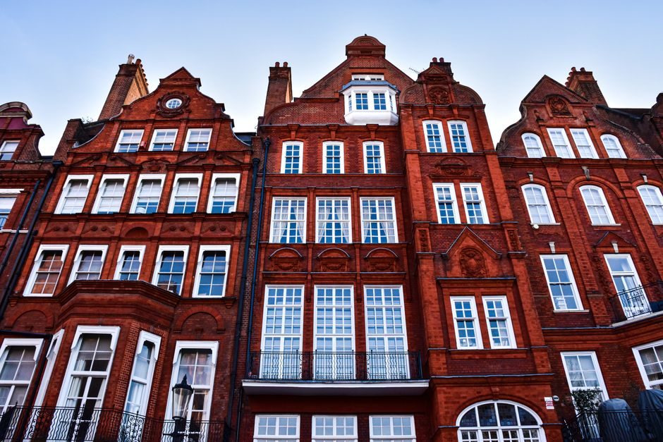Low-angle view of traditional Victorian townhouse facades in London.