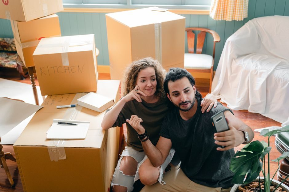 A young couple settling into the living room of their first home