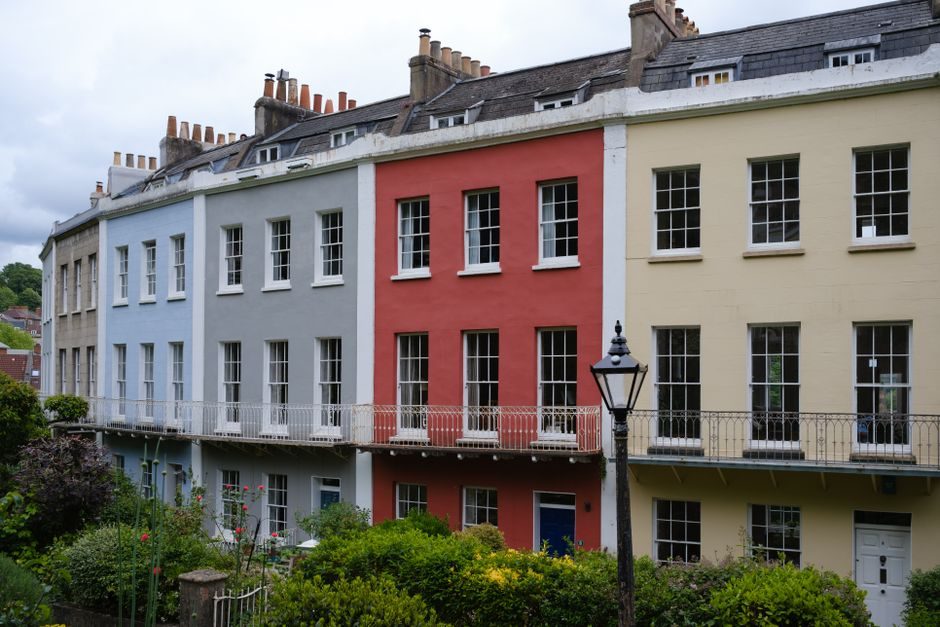 A row of colorful Georgian terraced houses in a quaint suburban neighborhood.