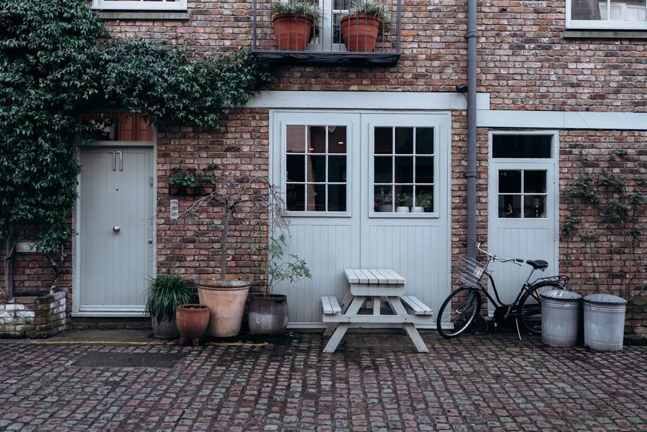Quaint courtyard scene in London with vintage bicycle, ivy, and rustic decor.