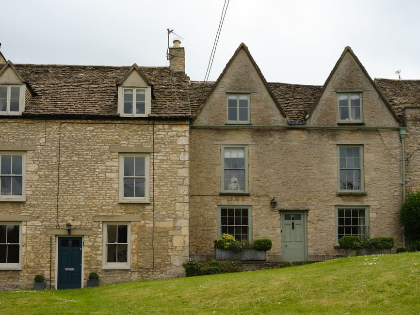 Quaint stone houses with steep roofs in the serene English countryside landscape.