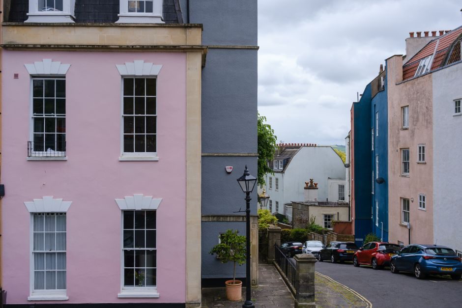 Colorful houses line a quiet urban street with parked cars and classic architecture.
