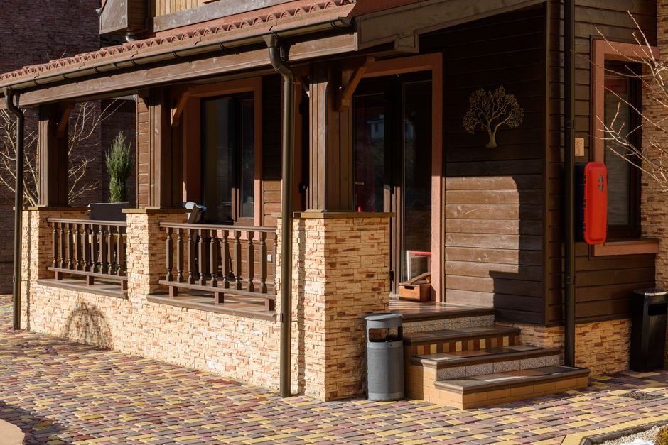 Beautiful wooden house exterior with stone accents and a cozy porch in bright daylight.