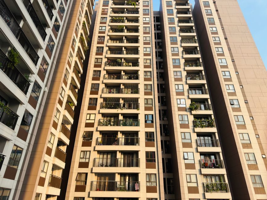 High-rise apartment buildings with balconies in an urban setting under a clear blue sky, emphasizing modern architecture.