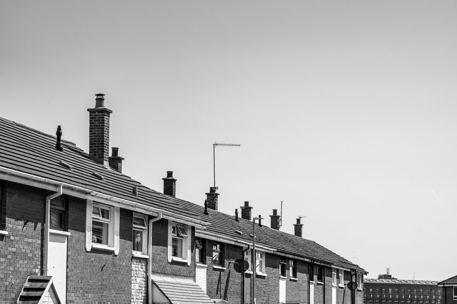 Monochrome view of classic Irish residential row houses with chimneys under a clear sky.
