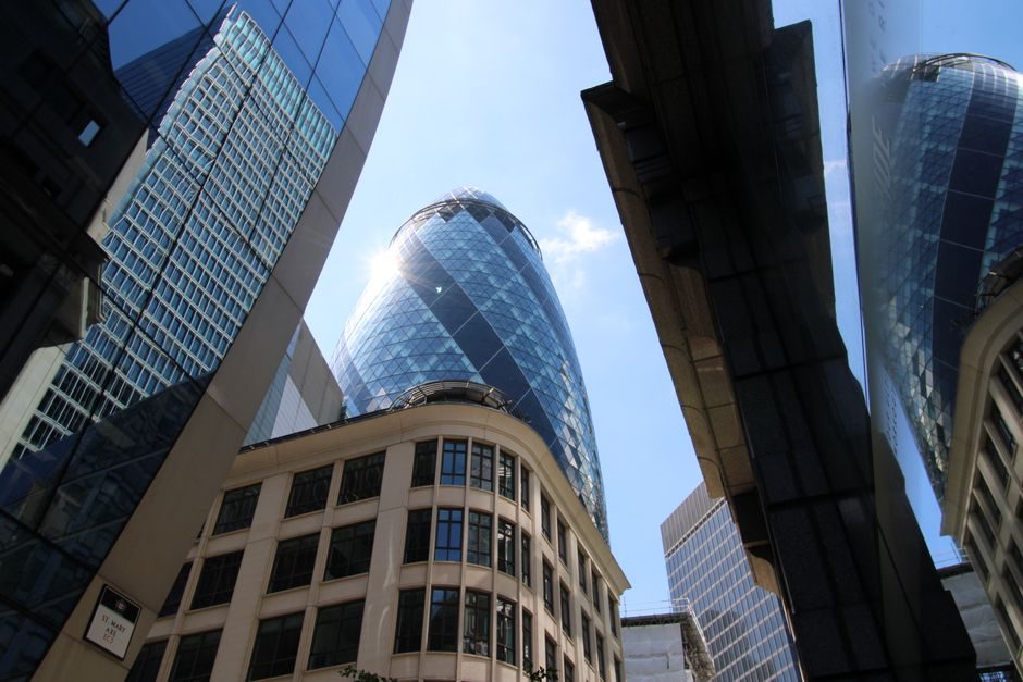 The Gherkin and modern buildings reflecting sunlight in London's financial district.