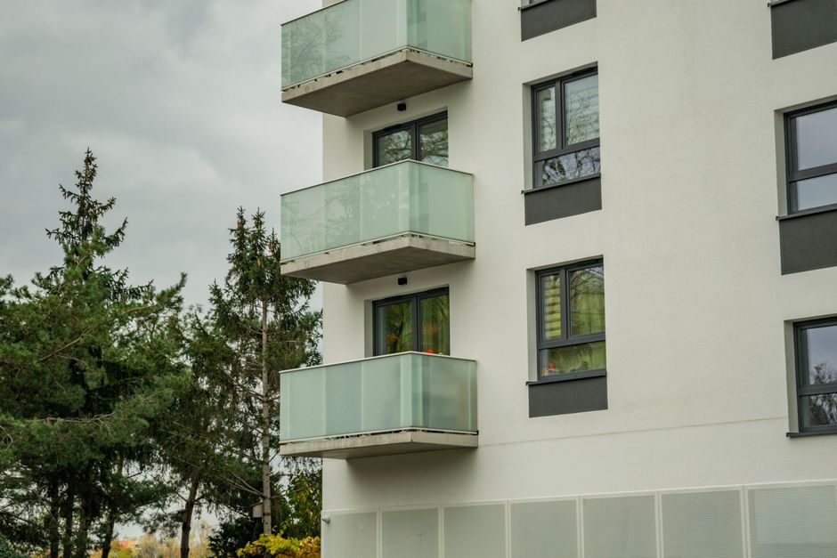 A modern UK new-build apartment building with glass facade against a clear sky