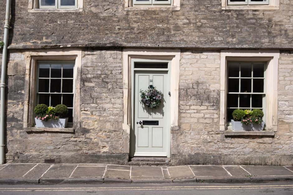 Cozy stone house exterior with potted plants and a decorative wreath on the door.