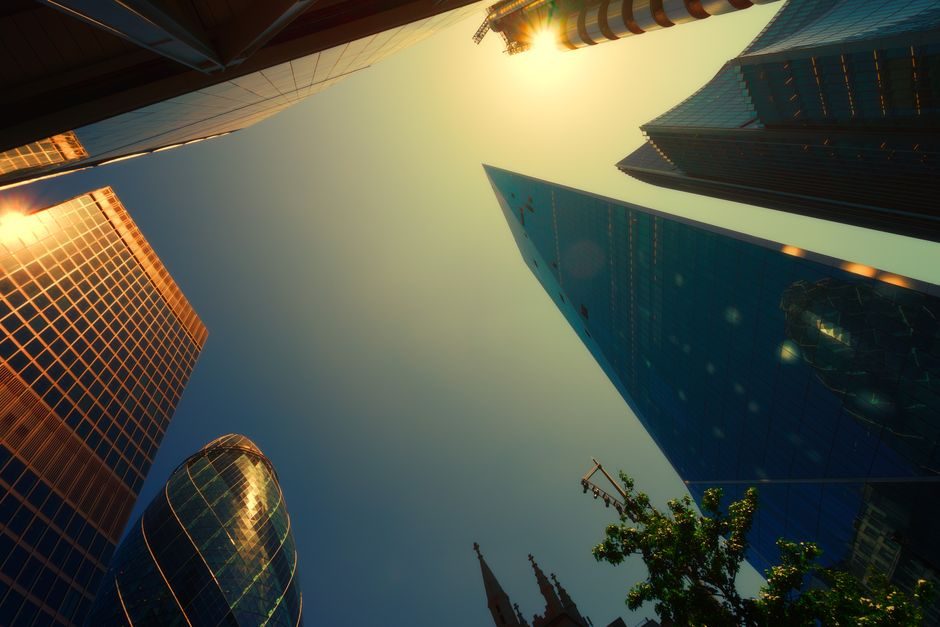 A stunning low-angle view of London's skyscrapers at sunset with warm lighting.
