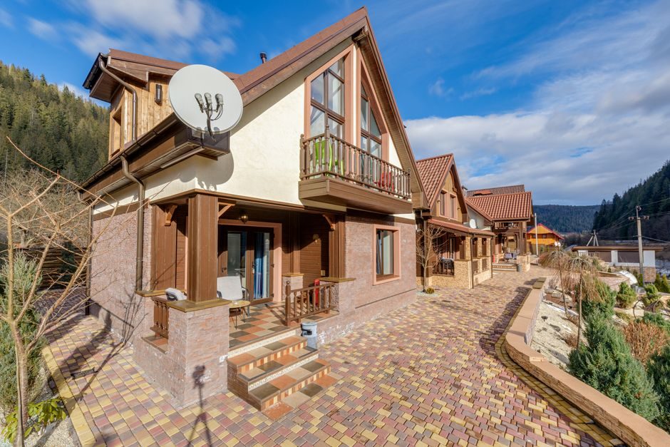 Beautiful modern wooden house with mountain views and vibrant paved walkway.