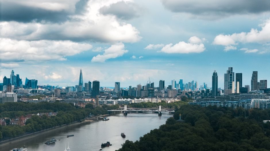 A breathtaking view of London's skyline with the River Thames flowing under dramatic clouds.