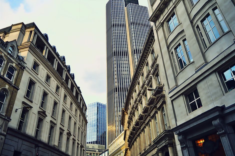 Low angle view capturing modern skyscrapers and historic architecture in an urban cityscape.